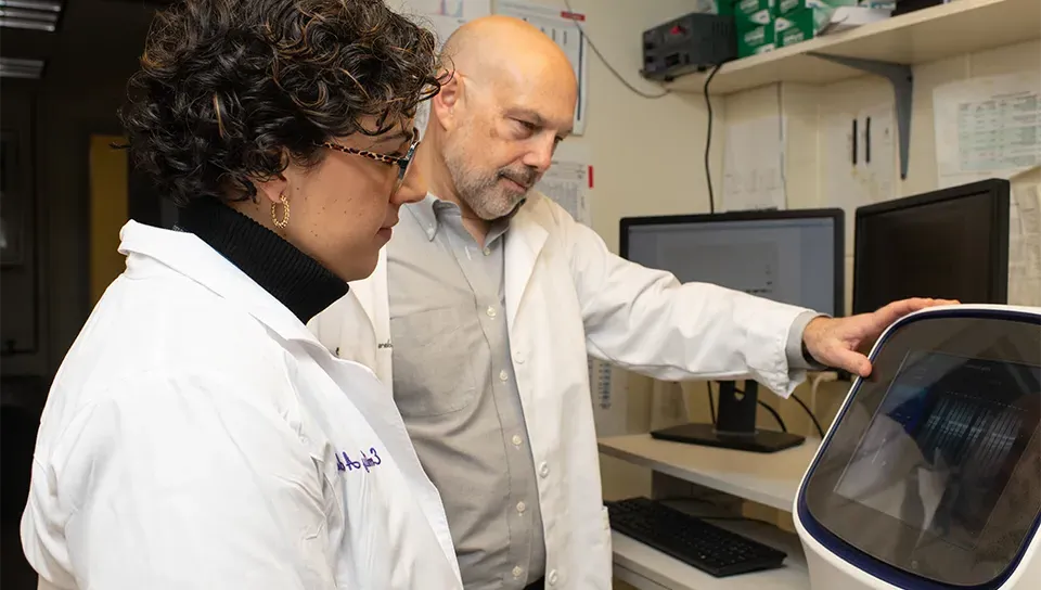 Derek Molliver in his lab works equipment with a graduate student