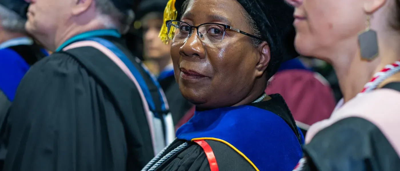 Carol J. Ewan Whyte, Ph.D., M.Sc. Director, U N E Graduate Programs in Public Health looks at the camera in a group of faculty at commencement