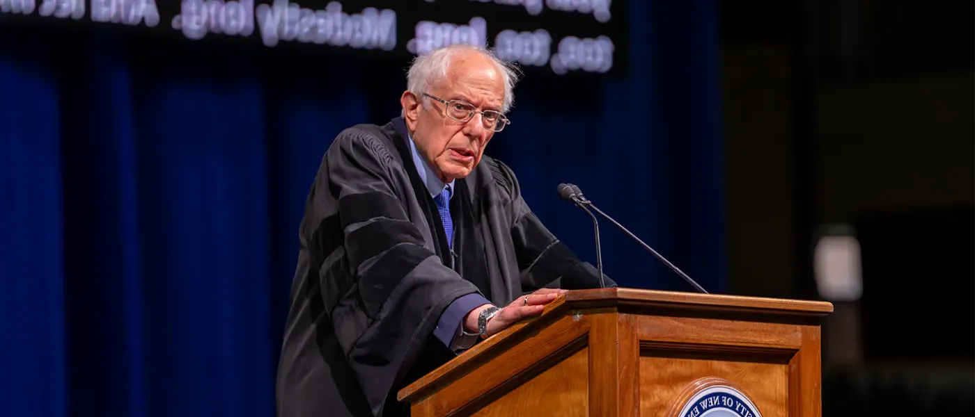 U.S. Senator Bernie Sanders stands at podium at U N E's 2024 graduation ceremony