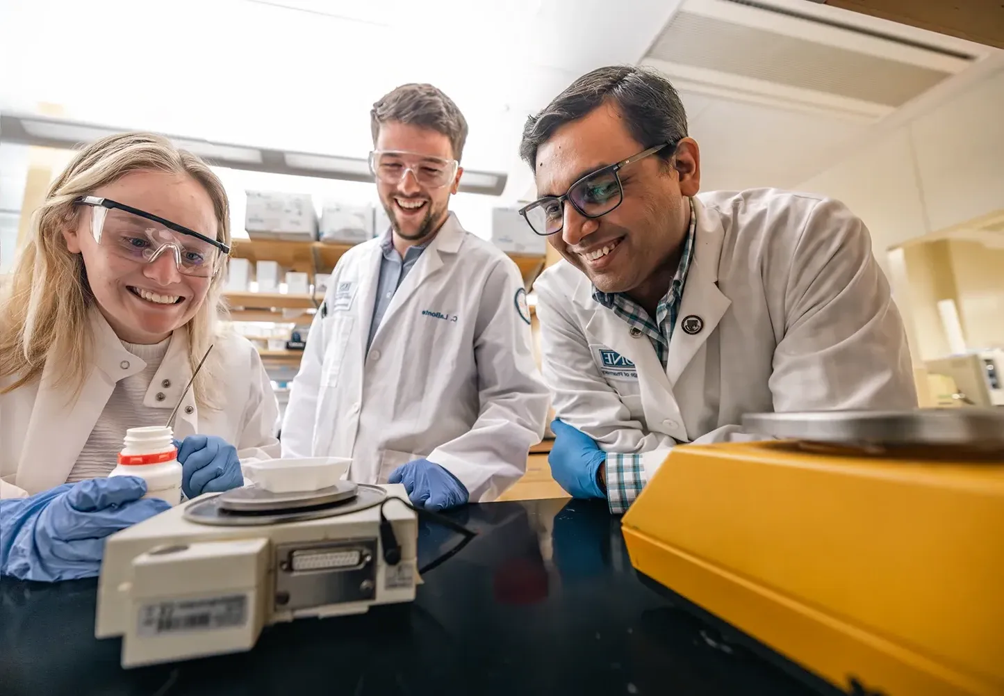 U N E faculty member and researchers Sri Mohan on the left stands next to two students working together in Mohan's lab